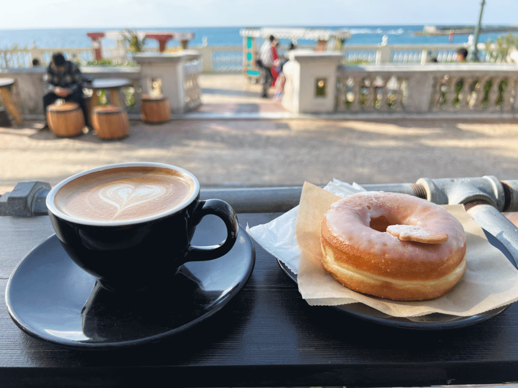 アメリカンビレッジの海が見えるカフェでコーヒーとドーナツを楽しむ様子