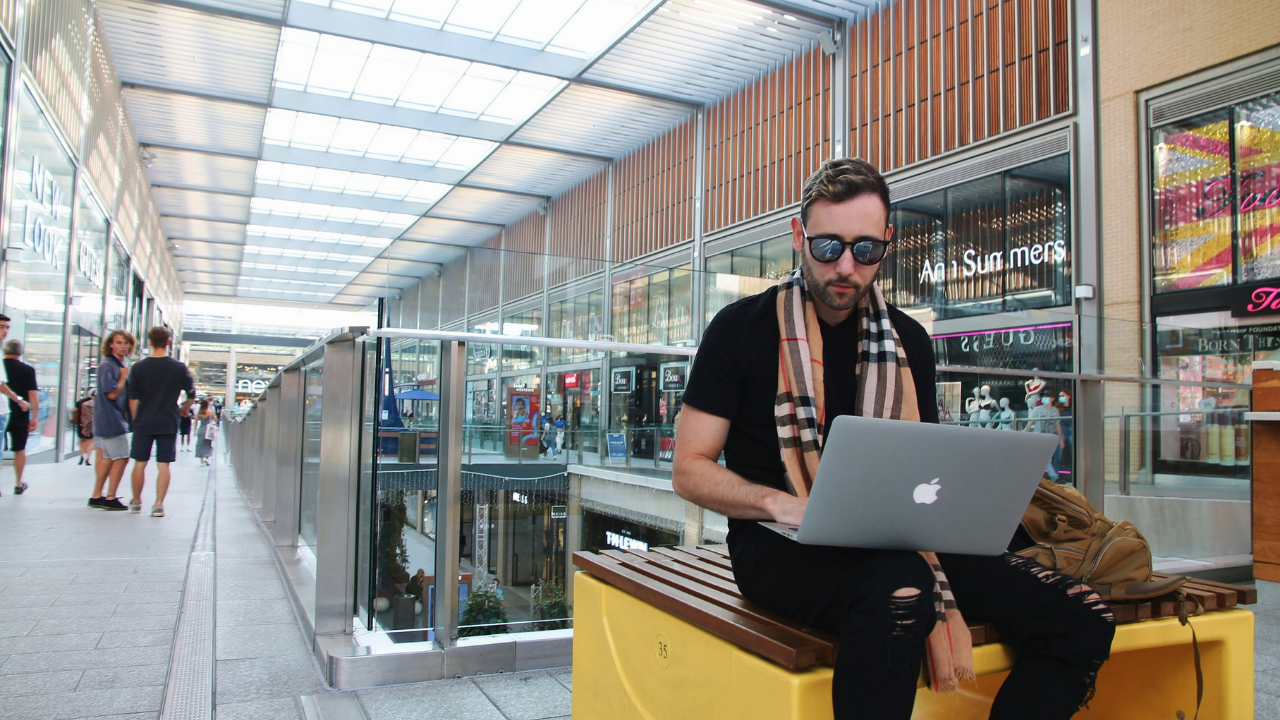 空港のような施設でノートパソコンを使って作業する男性のワーケーション風景