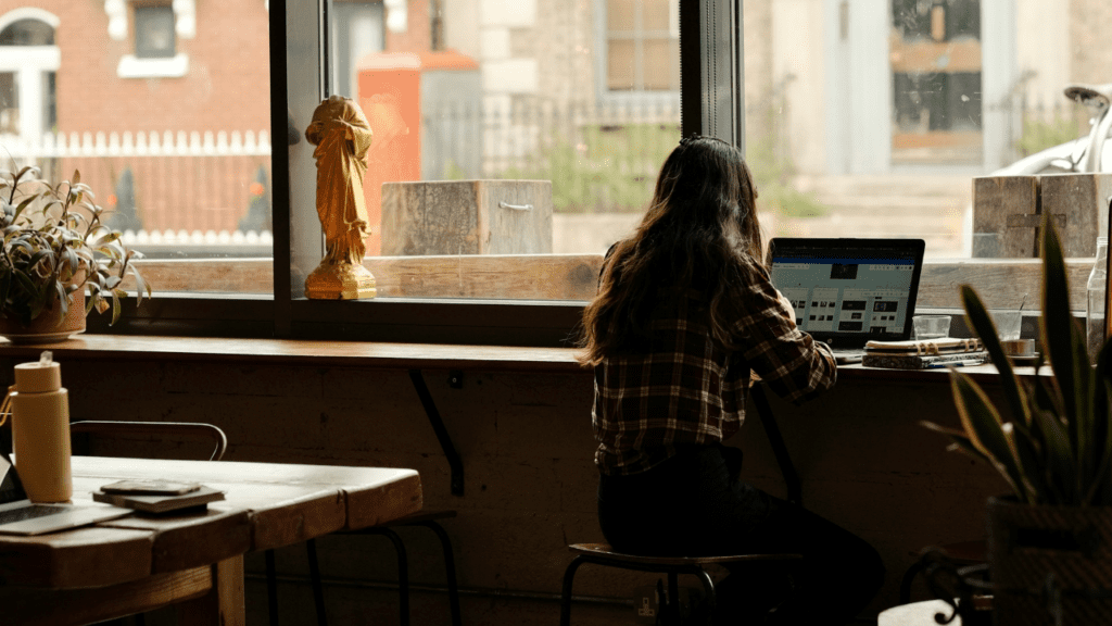 窓際でノートパソコンを使って作業しているワーケーションや外作業中の様子