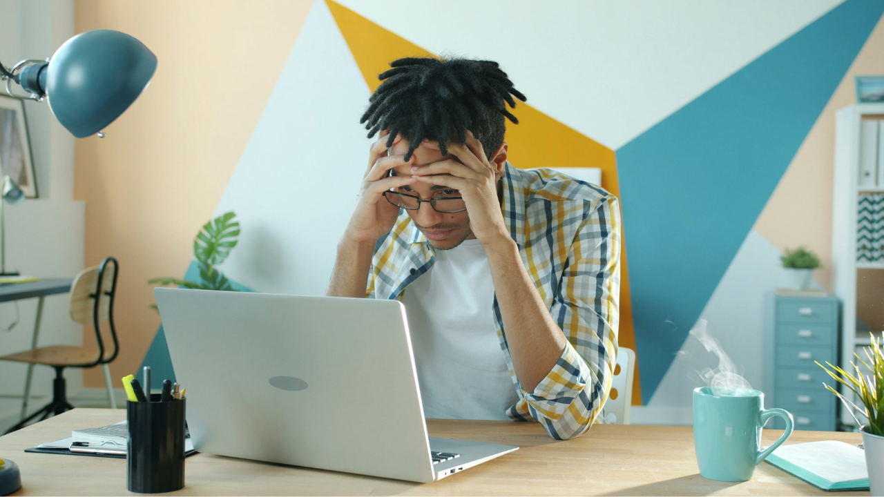 ホテルでノートパソコンを前に頭を抱え、Wi-Fiが繋がらず対処を考えている男性