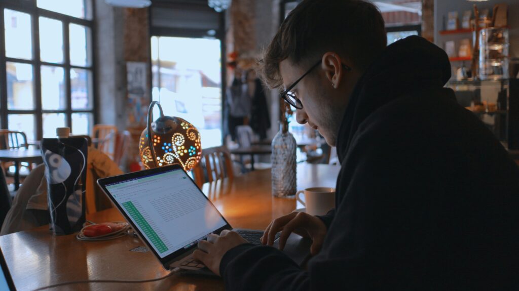 カフェでノートパソコン作業をする人と画面の覗き見リスク