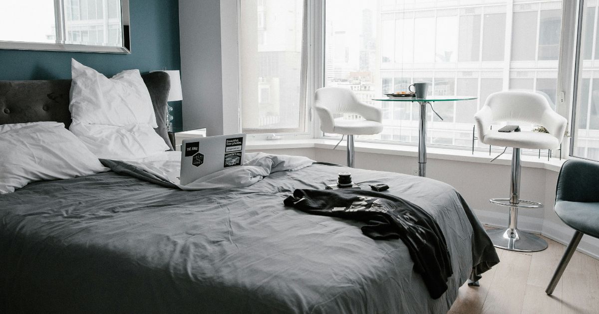 ホテルの部屋でノートパソコンとスーツケースを使うワーケーション環境のイメージ