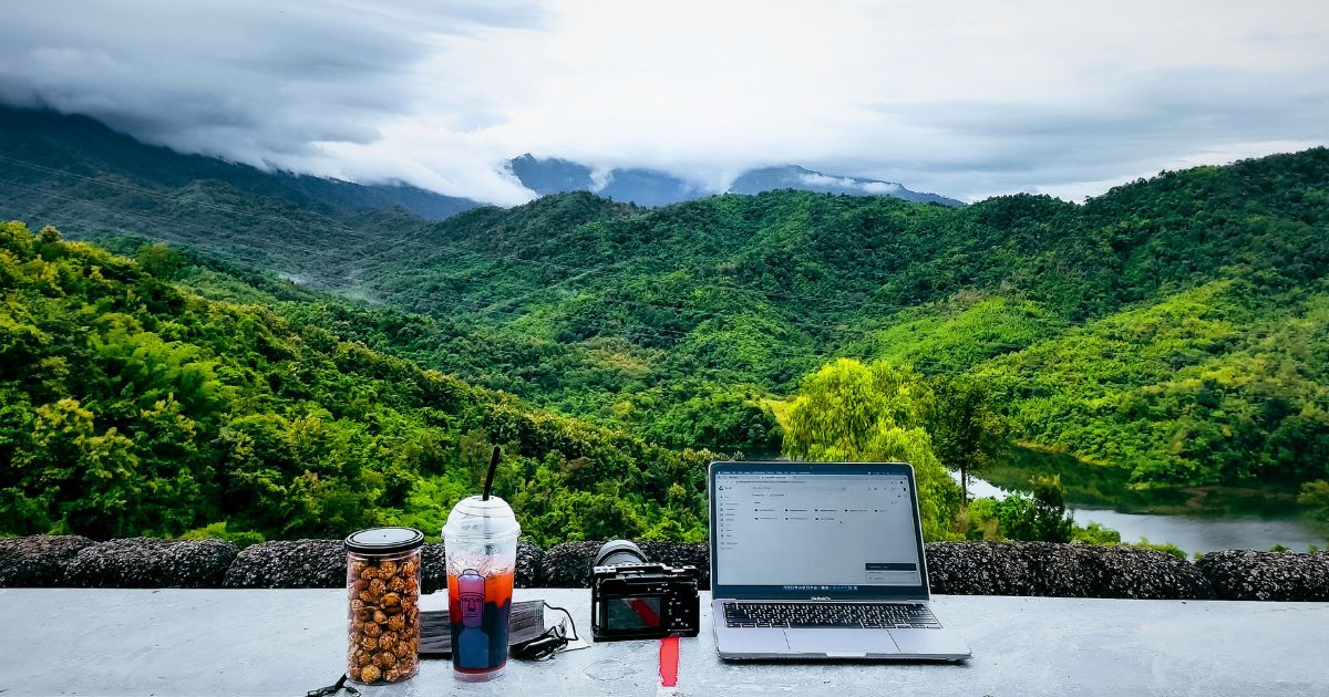 自然の中でノートパソコンとコーヒーを置いて作業するワーケーションの風景